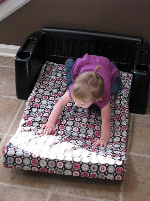 little girl sitting on sofa with cushion extended