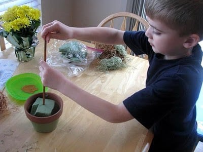 child placing dowel into floral foam