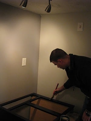 man painting cabinet with black paint