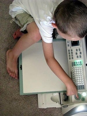 child pushing start button on Cricut machine