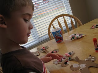 child gluing pom poms on garland