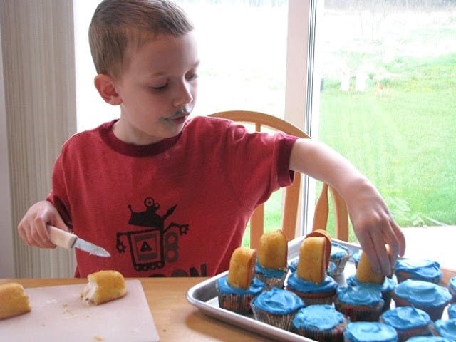 child putting half of a Twinkie onto cupcake