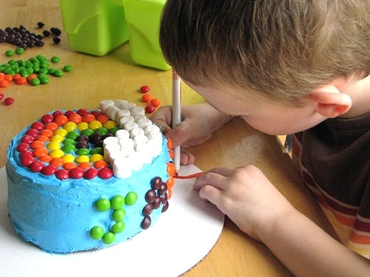 child decorating cardboard cake plate with markers
