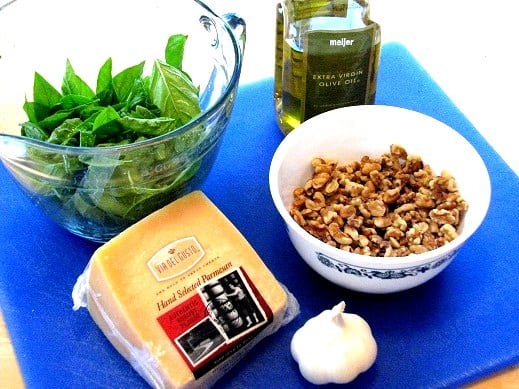 cheese basil garlic nuts and oil on a cutting board