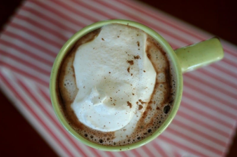 green mug of hot chocolate with whipped cream