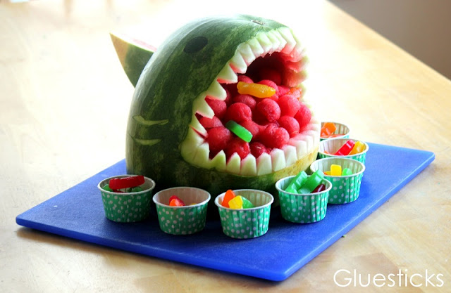 How to make a watermelon shark that is sure to be a hit at your next summer BBQ! Fill with fruit and gummy fish for a fun added detail!