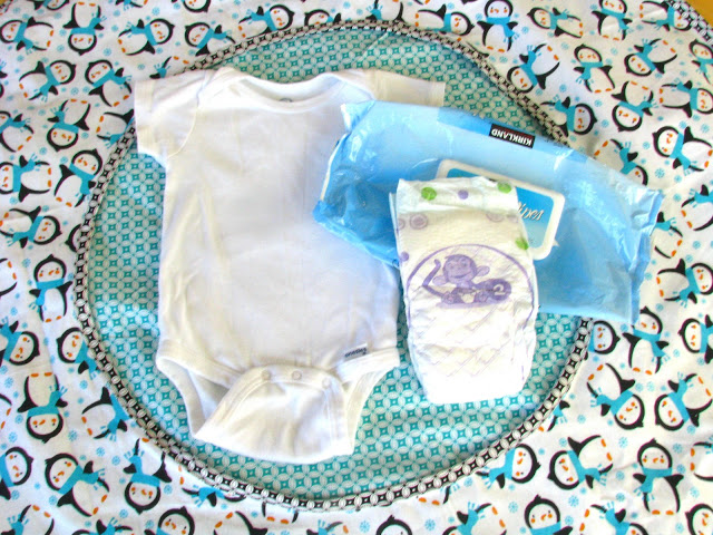 onesie and diapers and wipes on changing pad