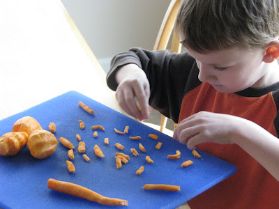 child cutting orange fondant into pieces to resemble macaroni