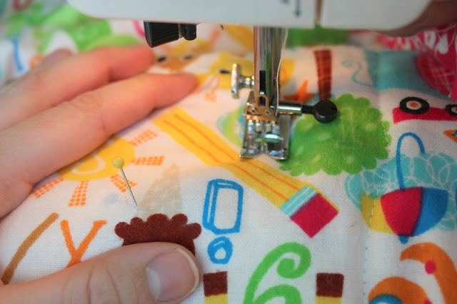hand pushing fabric through sewing machine