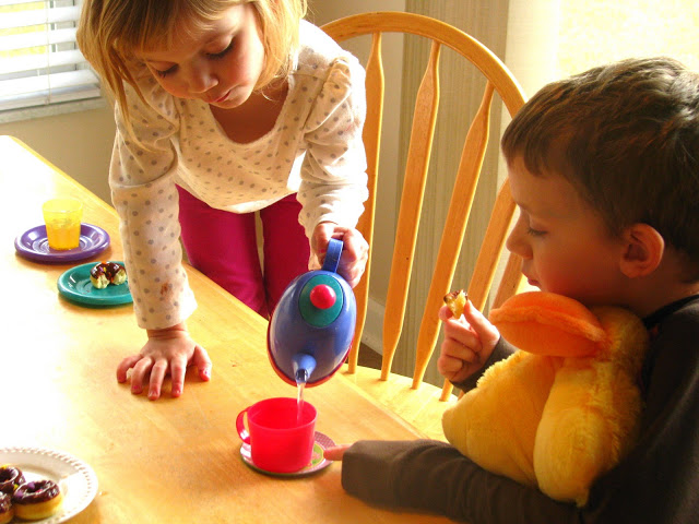 child pouring water from toy tea pot