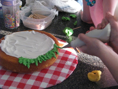 piping green frosting onto cake to look like lettuce
