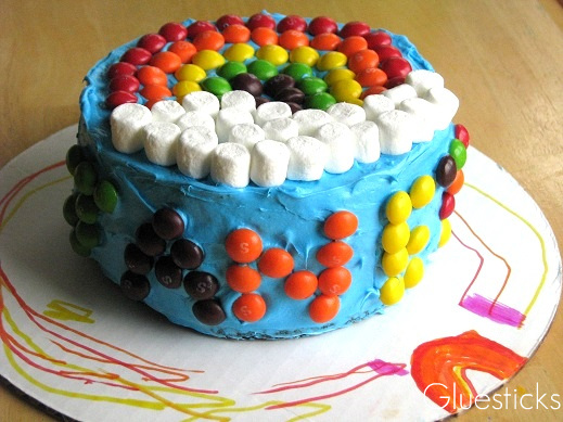 small blue cake with skittles in the shape of a rainbow