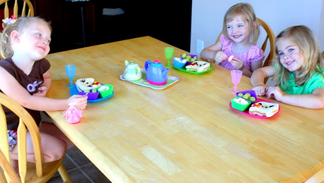 3 little girls eating sandwiches at kitchen table