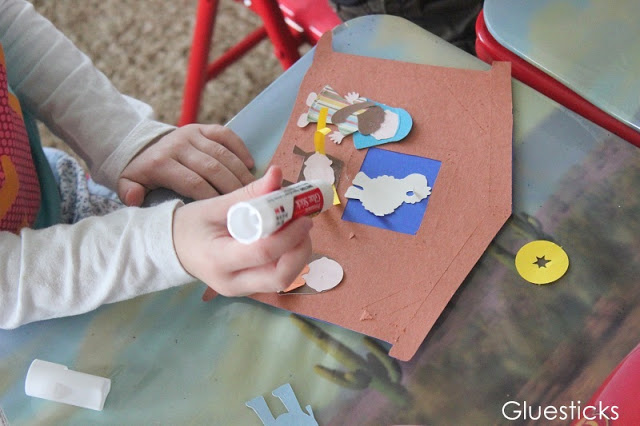 child gluing nativity scene characters onto manger with glue stick