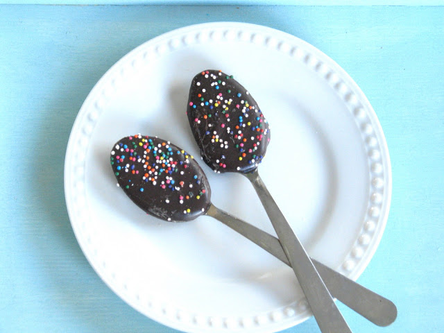 two chocolate covered spoons with sprinkles