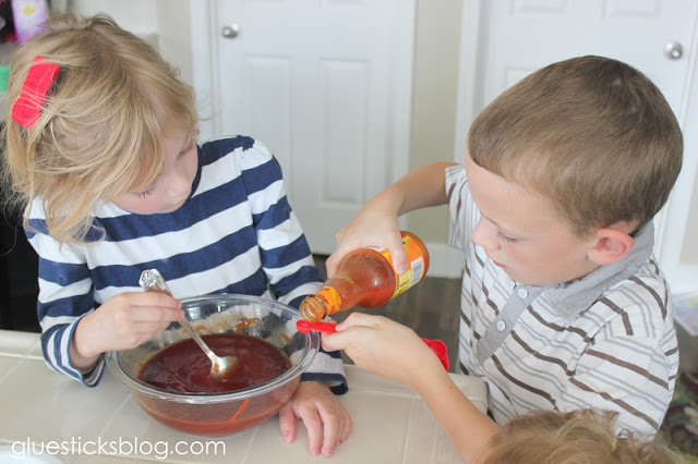 child pouring in hot sauce into teaspoon