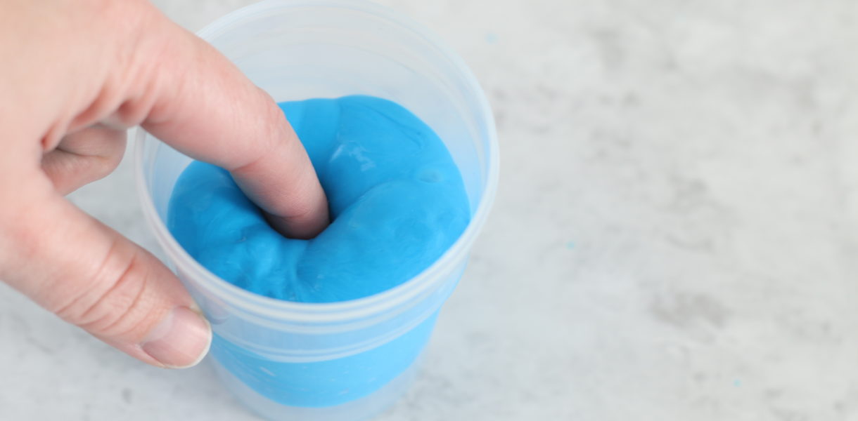 finger pushed into cup of putty