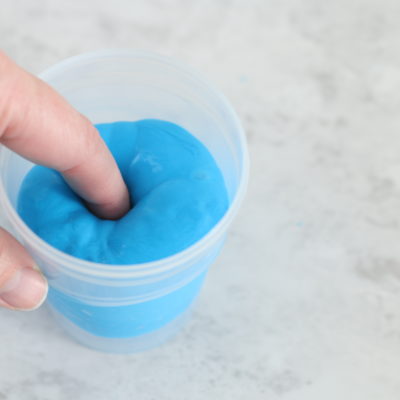 finger pushed into cup of putty