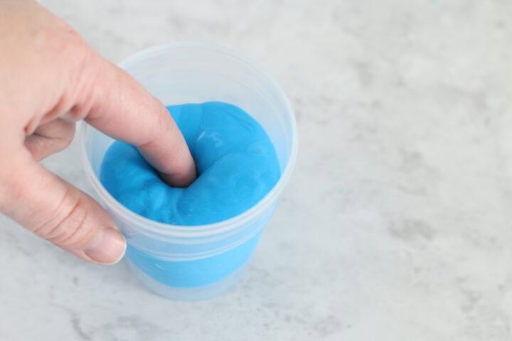 finger pushed into cup of putty