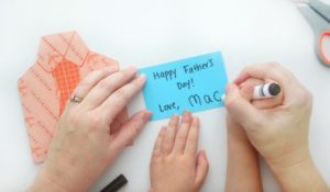 mom and child writing message inside card