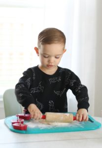 child rolling out salt dough