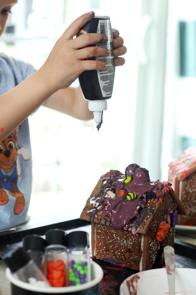 child pouring black icing over pop tart house