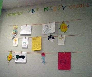 wall with child's artwork displayed on strings