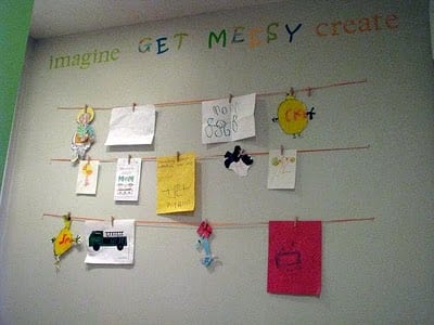 wall with child's artwork displayed on strings
