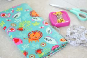 folded fabric with pins, scissors and a measuring tape