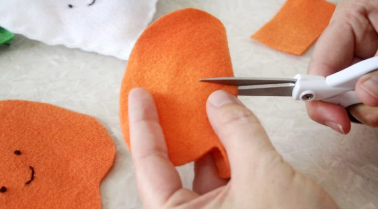 Pumpkin folded in half and scissors cutting a slit in the back.