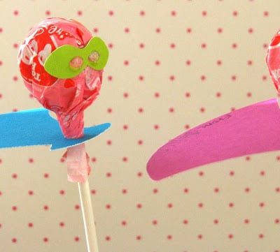 two lollipops with paper capes and masks
