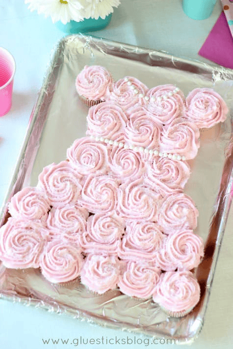 Cupcakes arranged in the shape of a dress and frosted with pink frosting.