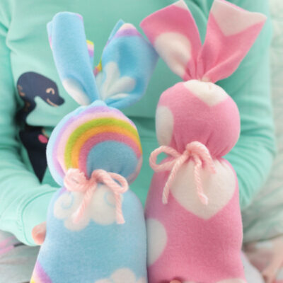 young girl holding two fleece bunnies