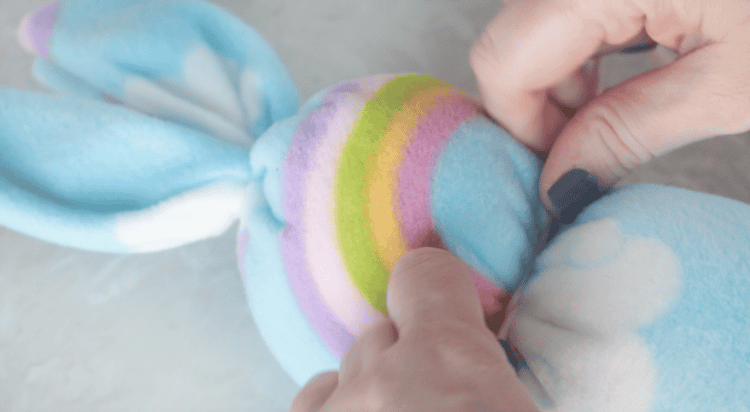 Hands tying a piece of yarn around fleece bunny.
