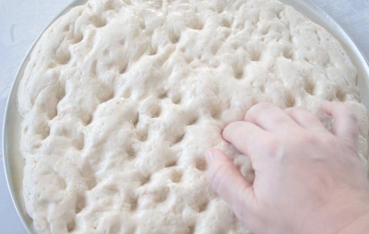 fingers poking dimples into dough