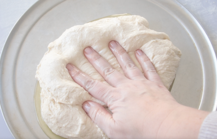 hand pressing dough onto pan