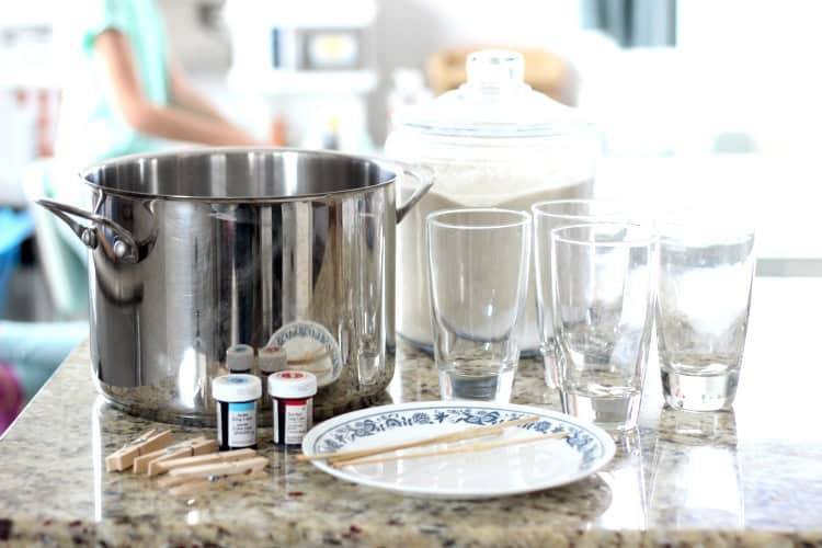 Stainless steel pan, jars, food coloring, skewers, a jar of sugar, and a plate.