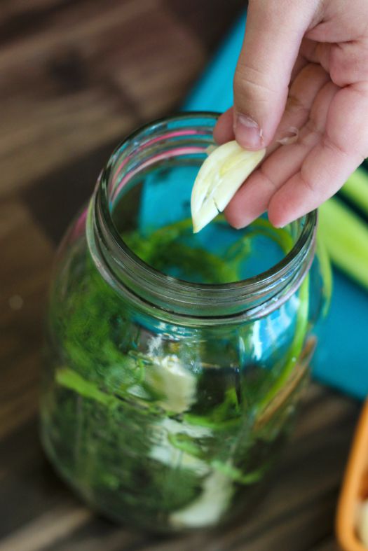 hand adding garlic to jar