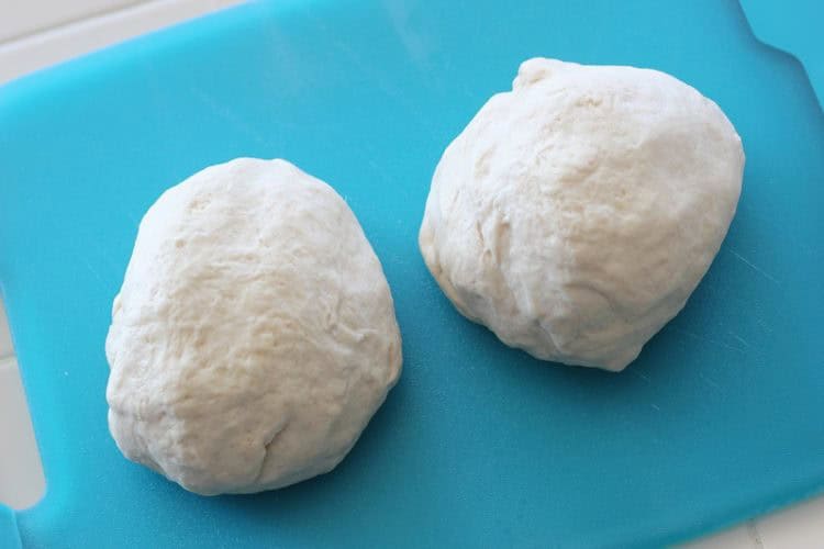 Two balls of bread dough on cutting board.