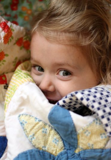 little girl wrapped in quilt