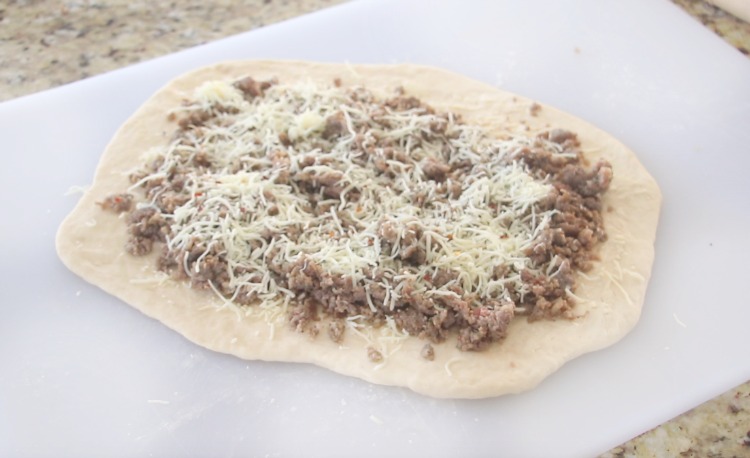 dough rolled out with butter spread across and toppings