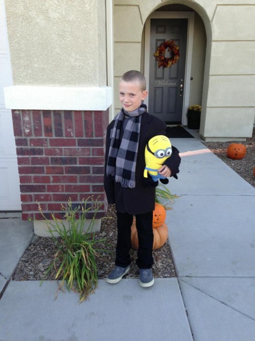 little boy in Gru costume holding a minion toy