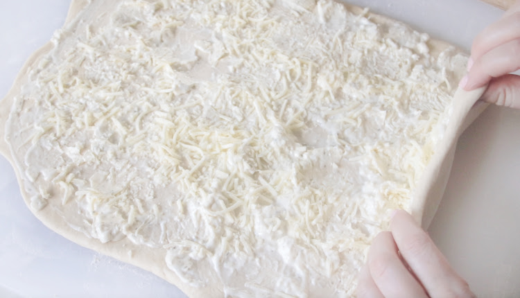 hands folding dough in half with filling in the center