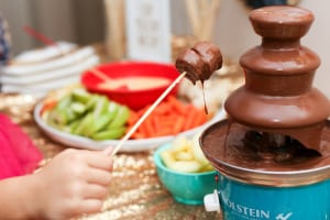 child with skewer dipping food into chocolate fondue