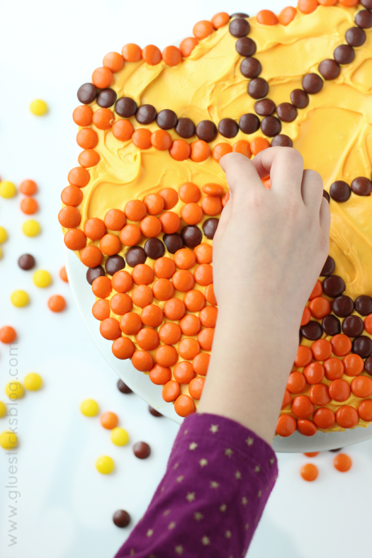 child helping add candies to pull apart basketball cake