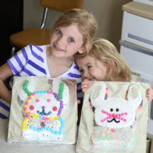 Two little girls with two Easter bunny cakes.