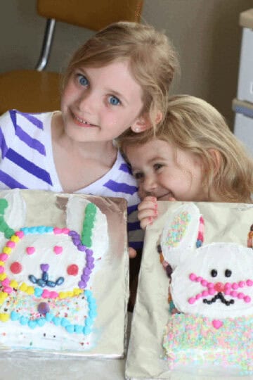 Two little girls with two Easter bunny cakes.