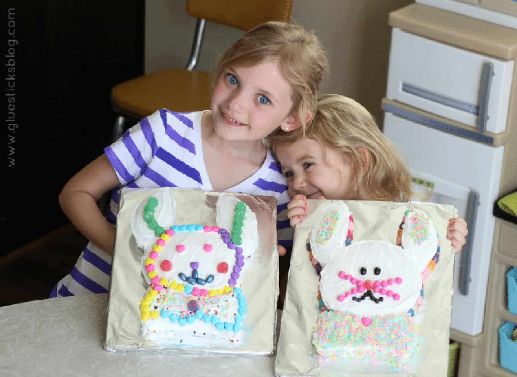 Two little girls with two bunny cakes.