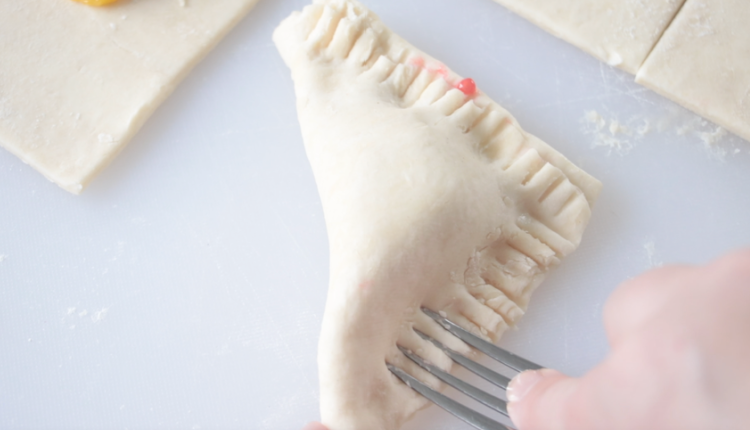 unbaked lemon raspberry turnover with fork crimping the edges