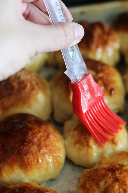 pretzel rolls being brushed with butter